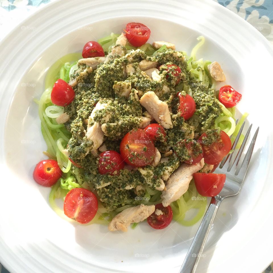 Chicken and cherry tomatoes with pesto sauce over zucchini noodles