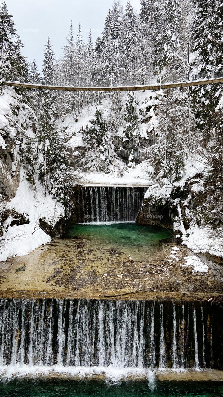 Scenic view of winter landscape with snow covered trees in Slovenian Alps. And beautiful waterfall in the mountains. Beauty of nature concept background.