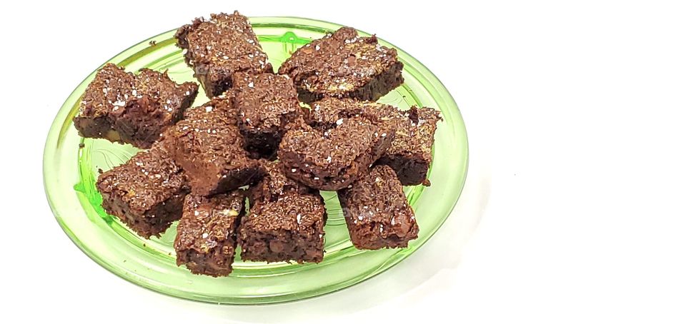 Chocolate brownies on a green glass plate with a white background 