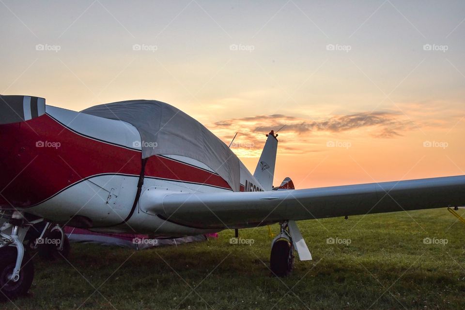 Piper Comanche parked in a field at sunrise