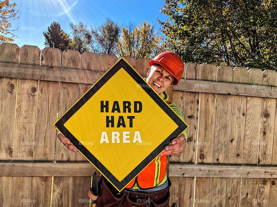 Woman construction worker holding sign, woman construction worker, holding a hard hat area sign, unconventional roles for women 