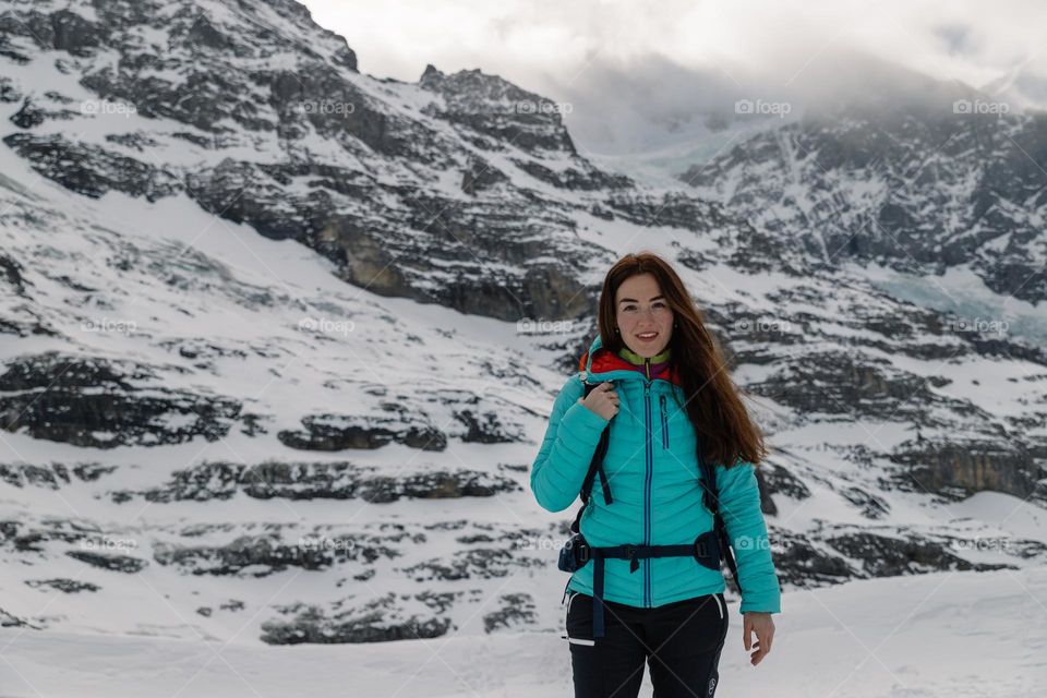 Woman posing while being on a hike in a beautiful mountains area, surrounded by glaciers and tall peaks.