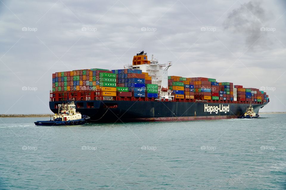 Fully laden Container ship being manoeuvred by tugs