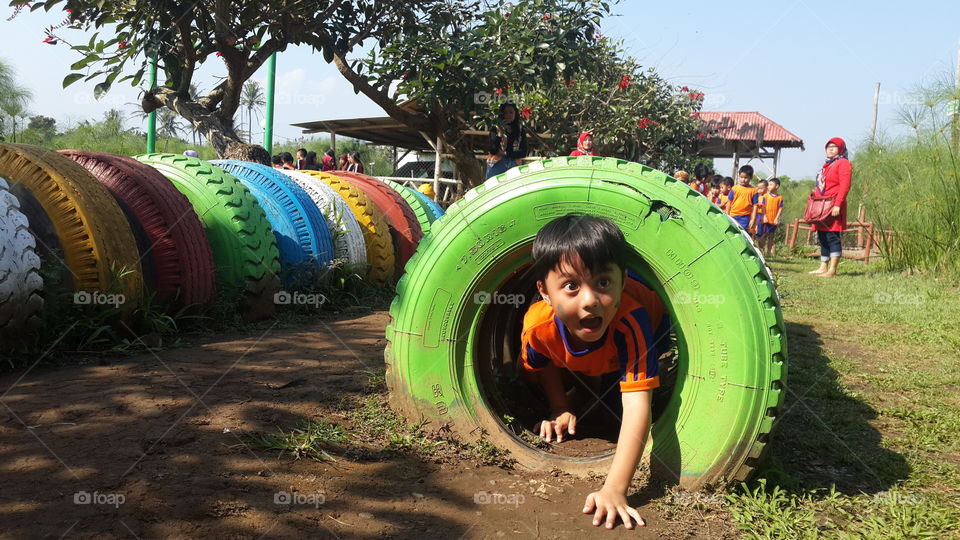 Boy crawling from tire from park