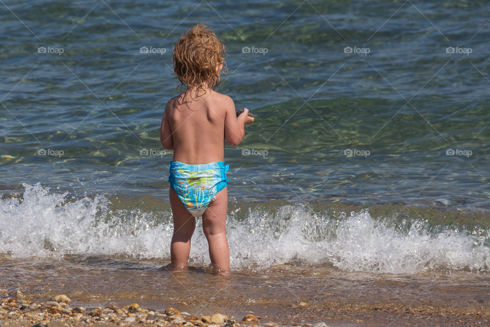 Back side view of a litle boy on the beach
