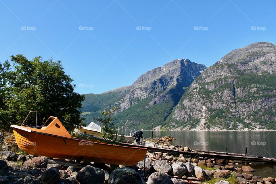 Scenic view of fjords with a boat on land in Eidfjord in sunlight during summer 