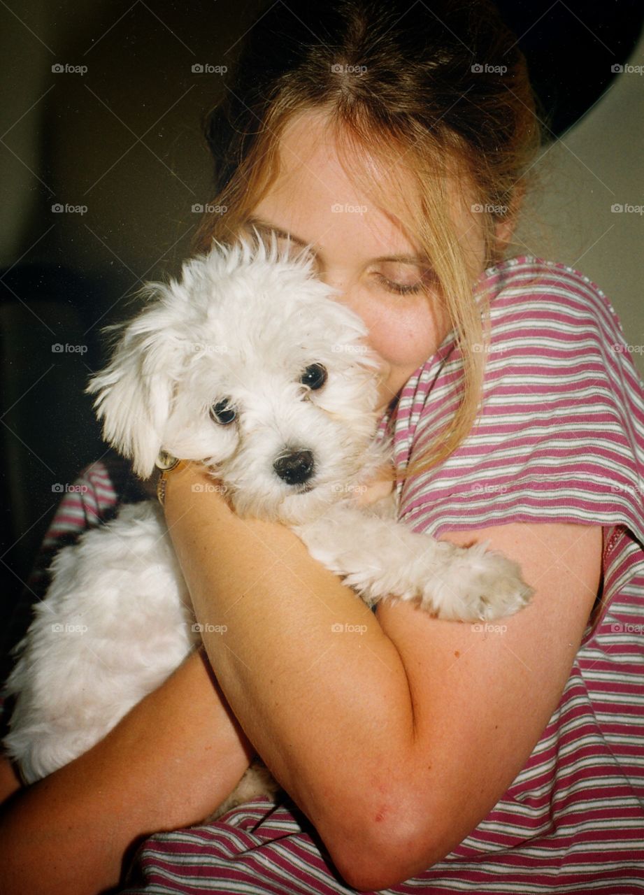 Happiness is a warm puppy. A Maltese puppy cuddles with his new owner