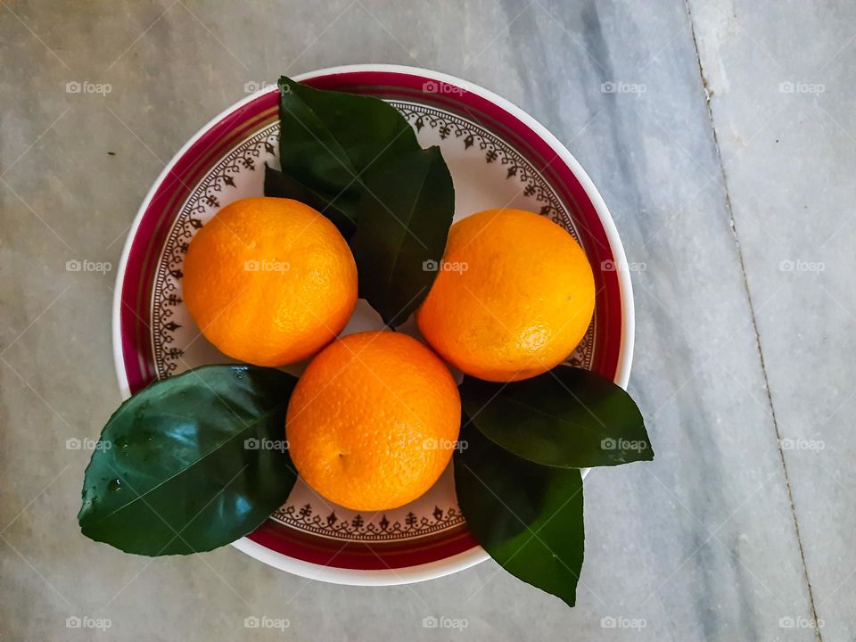 Tangerine on a bowl with its leaves