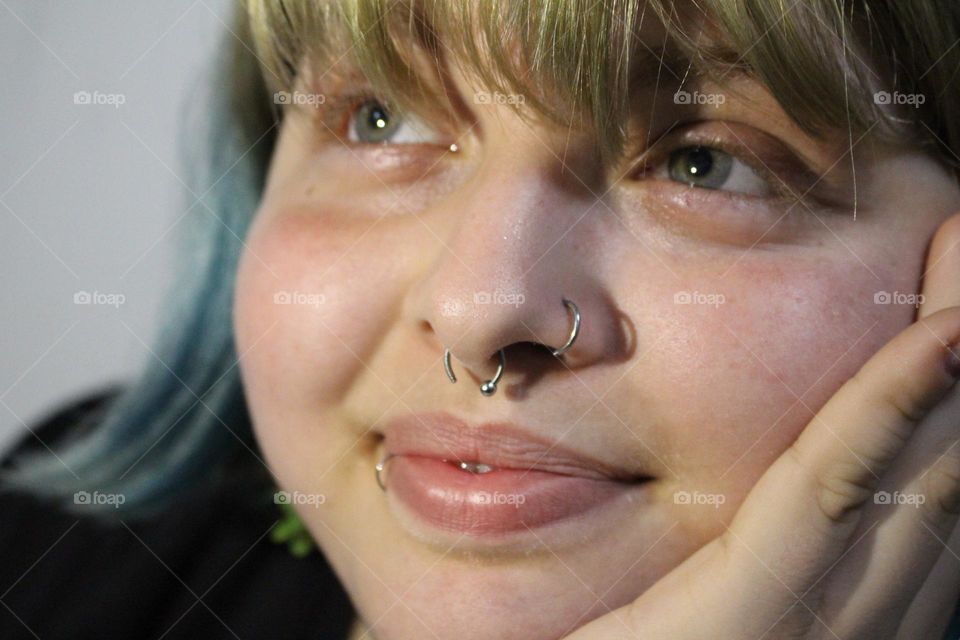 adolescente mujer con piercing en la nariz y boca tes blanca y pelo rubio y azul y ojos celestes