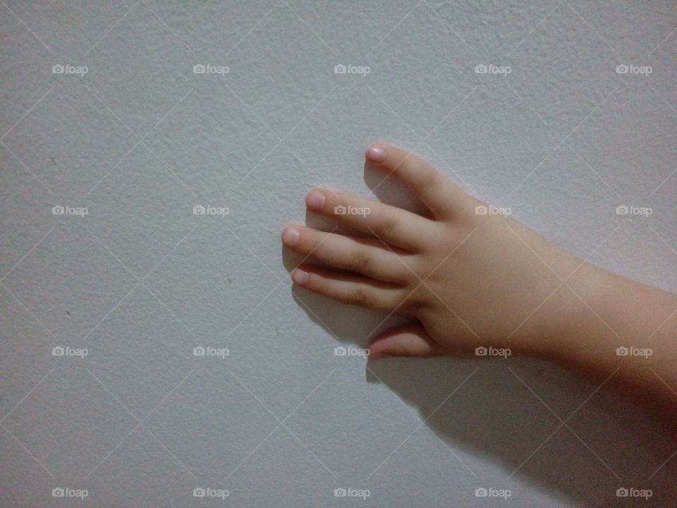 Child's hand touching the white wall