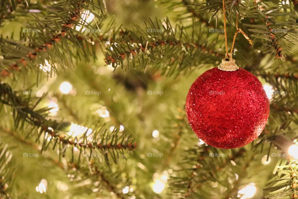 Red sparkly ornament on Christmas tree.