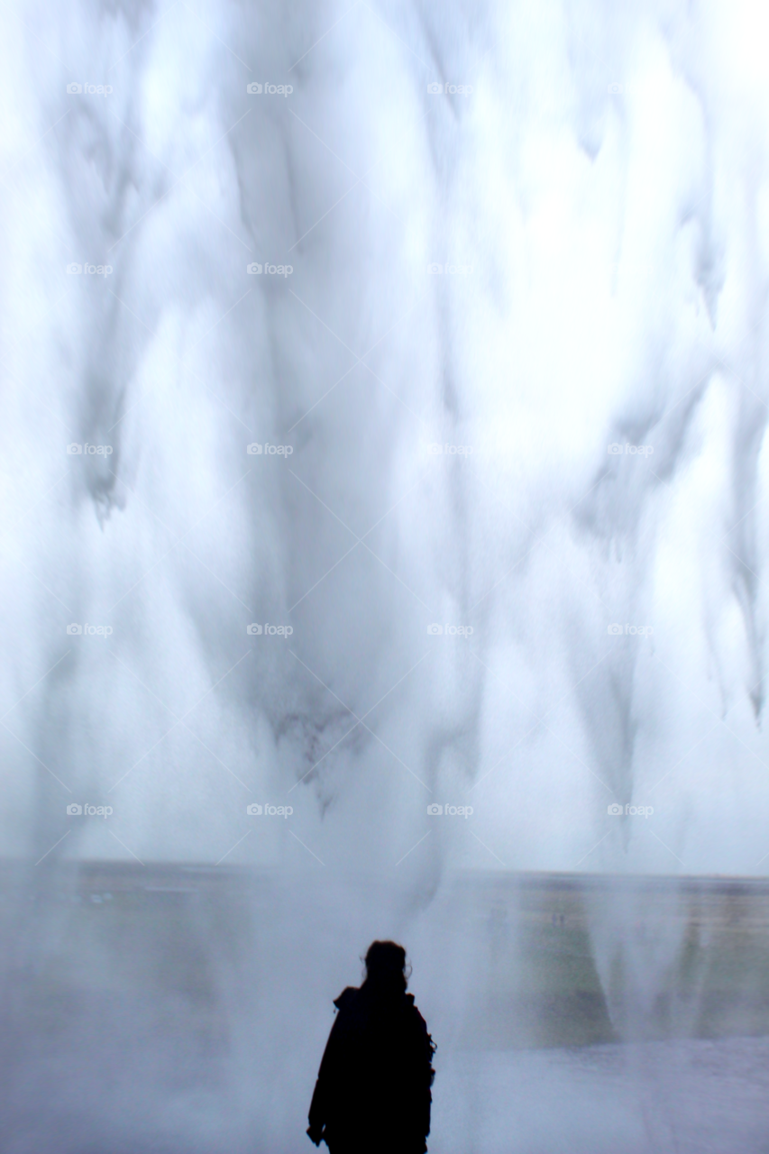 A woman silhouette in front of the skogafoss waterfall in Icelandic countryside 