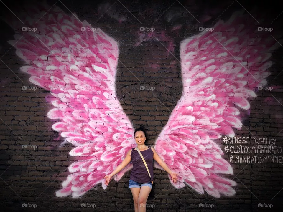 Pink angel wings mural on brick wall. Wings of Whimsy. Mural art Minnesota. City of Mankato