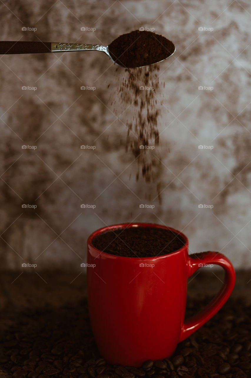 Red coffee mug with coffee grind pouring over 