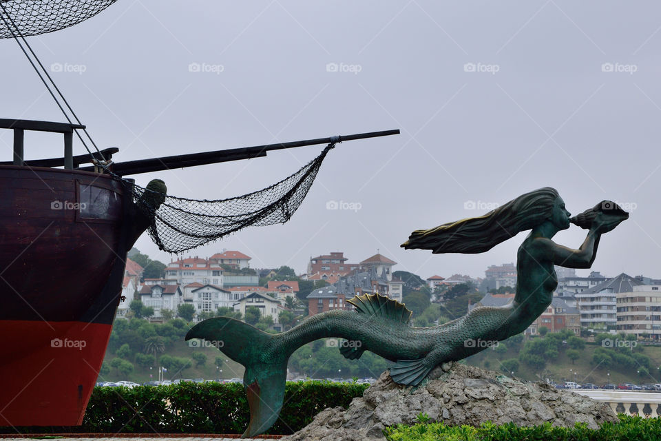 Mermaid statue of Sirena Magdalena in the Magdalena Peninsula, with the city of Santander in the background.