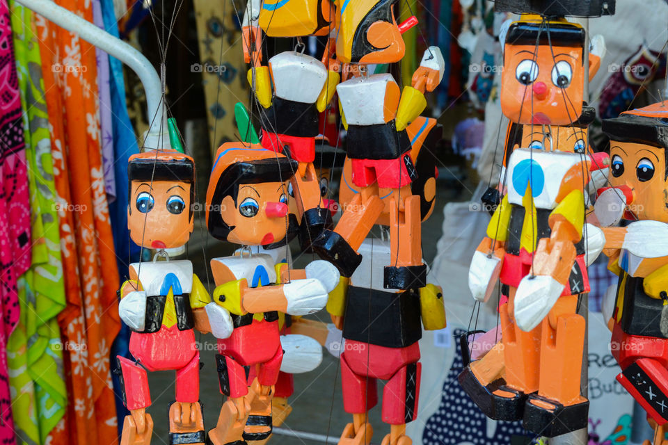 A bunch of wooden Pinocchio dolls hanging from an outdoors souvenir shop in Greece