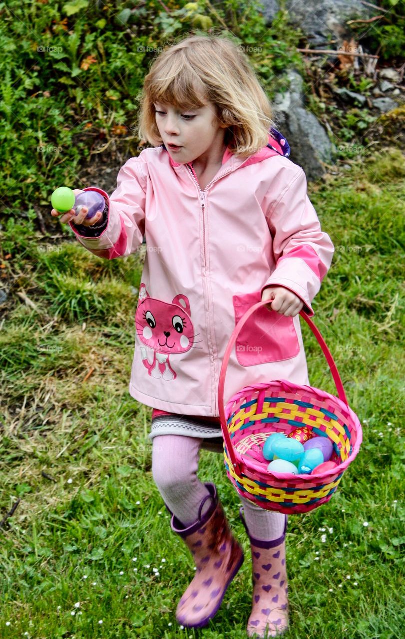 Girl in pink shows amazing facial expression during Easter egg hunt