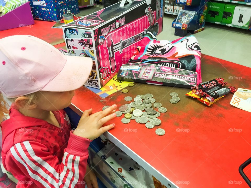 Young girl is shopping toys for her one saved money at Toystore in Malmö Sweden.