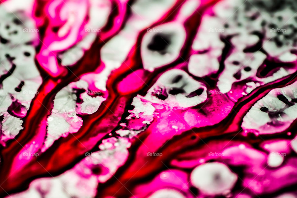 Black and pink refill ink spilled onto the white sink and the ink mixed into abstract blobs and patterns.