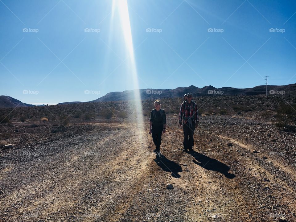 Active young couple hiking in the desert with blue sky and sunlight beaming down.