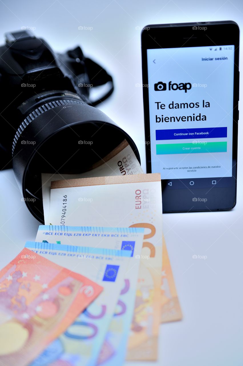 An Smartphone showing Foap welcome page next to a camera with a lot of money in euros coming out of the lens.
