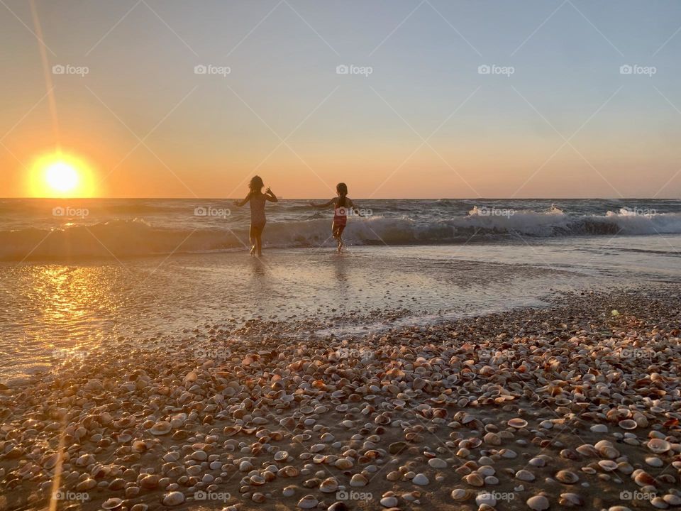 Two girls jumping on the waves during sunset