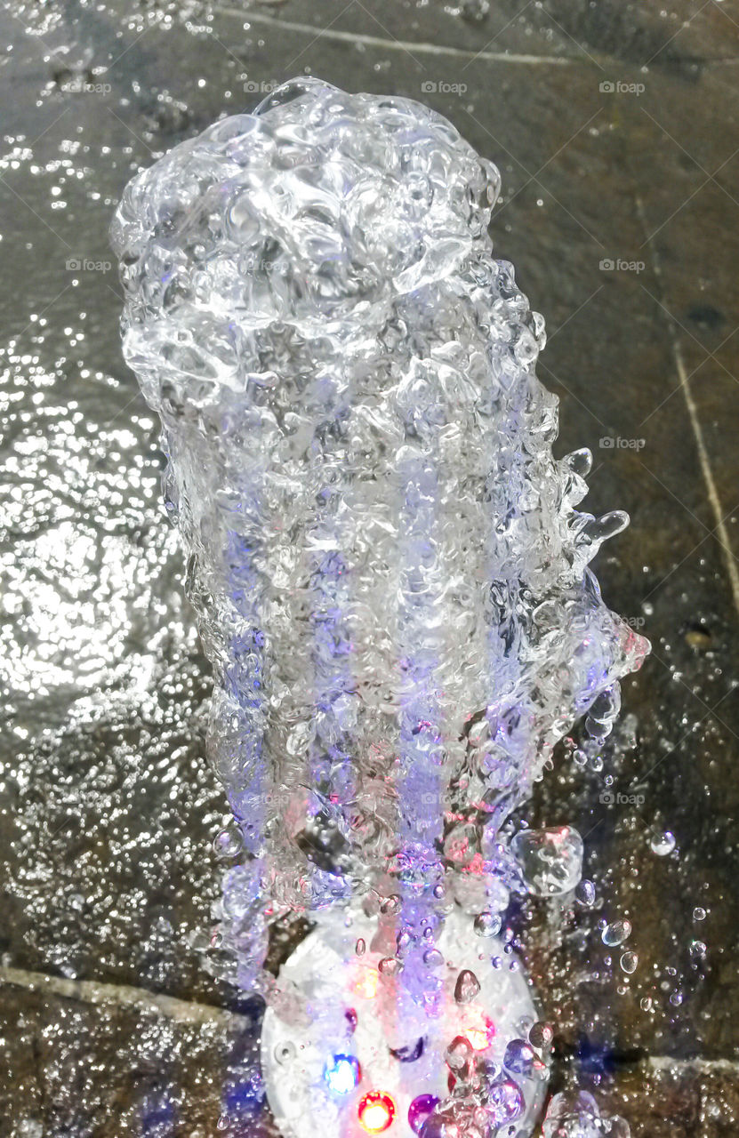 water in motion: Close up of water splash from a fountain with colored light