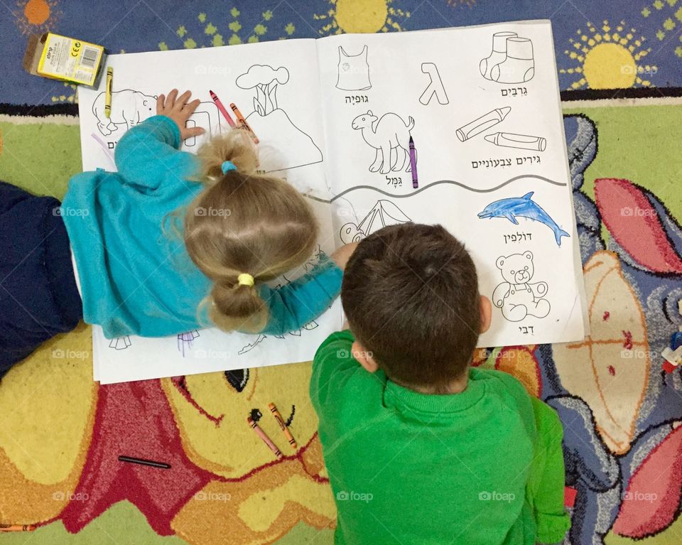 Elevated view of a brother and sister coloring sketch in book