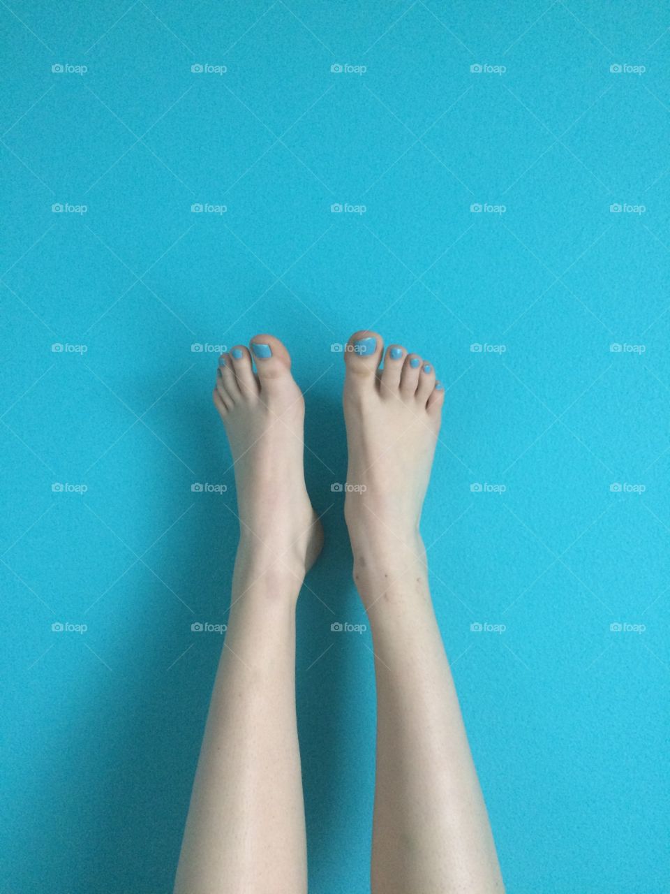Feet with blue painted toes on a blue wall.