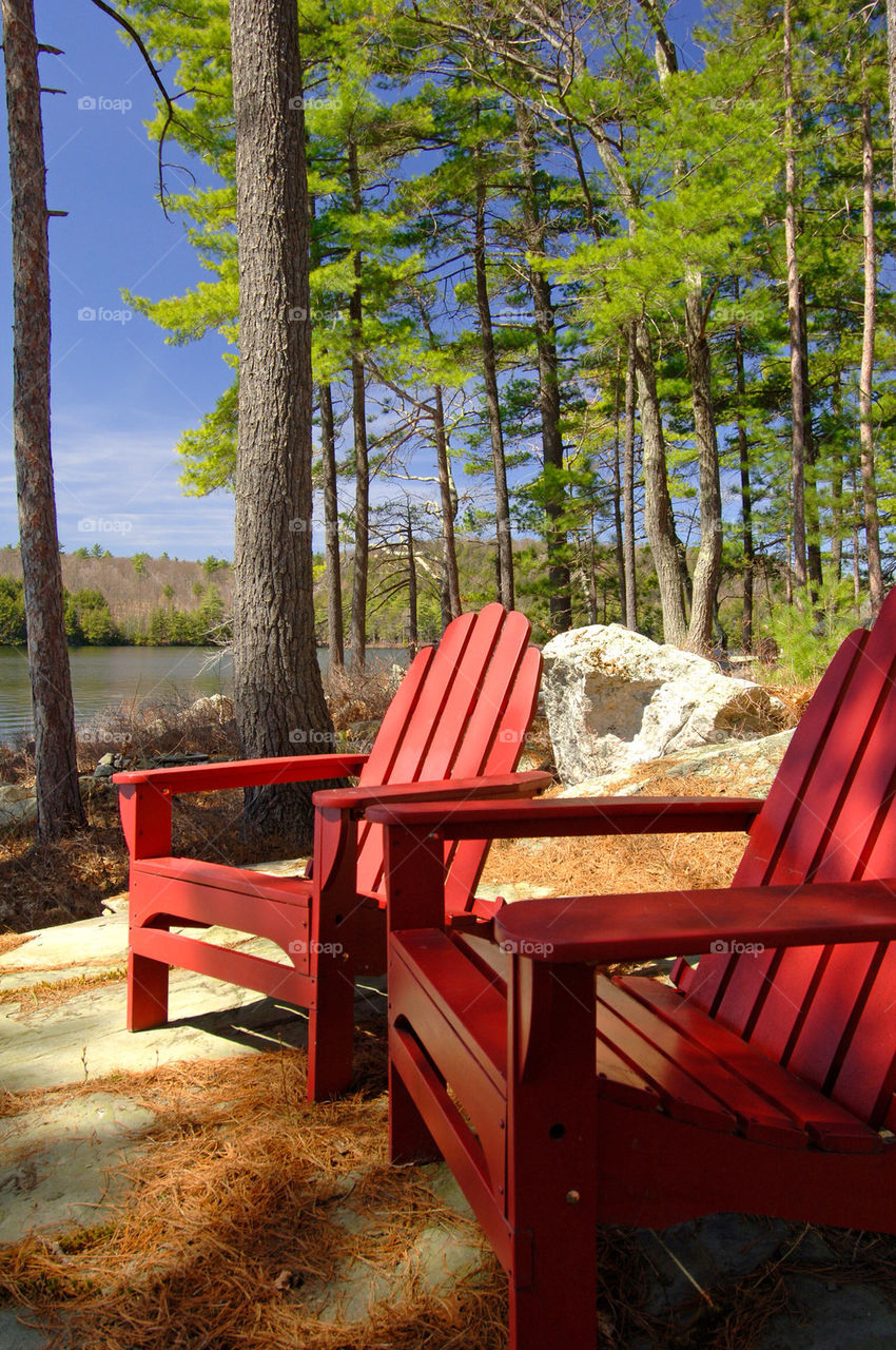 Two red chairs sit by the lake On Lake Winnepesaukee