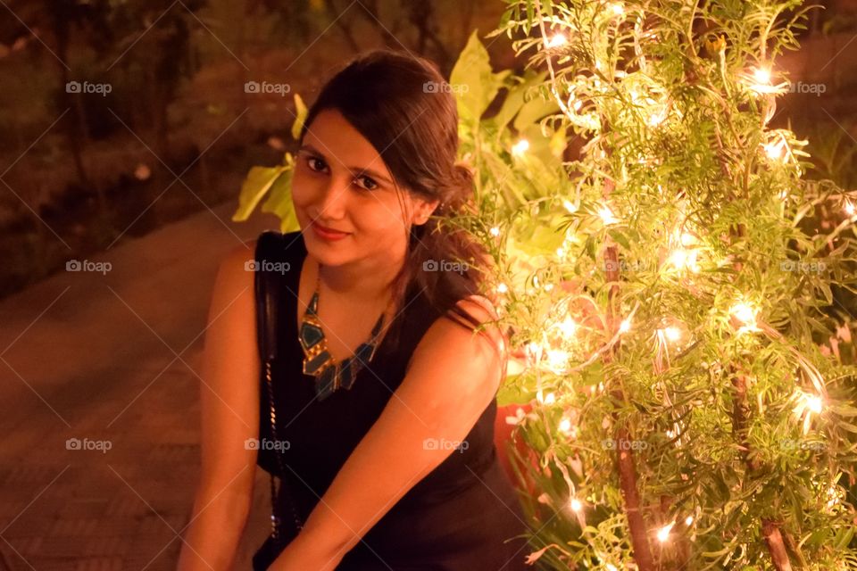 smile. picture of a bush decorated with lights and it's glow falling on the model