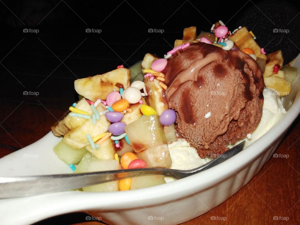 a bowl of banana split with chocolate ice cream and various toppings
