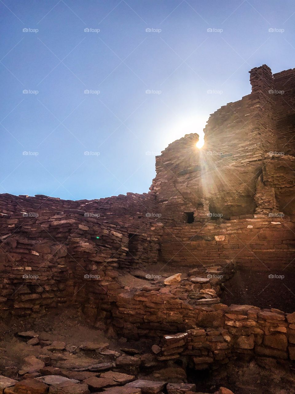 Red rock Pueblo in Arizona with sun shining through gap in rocks