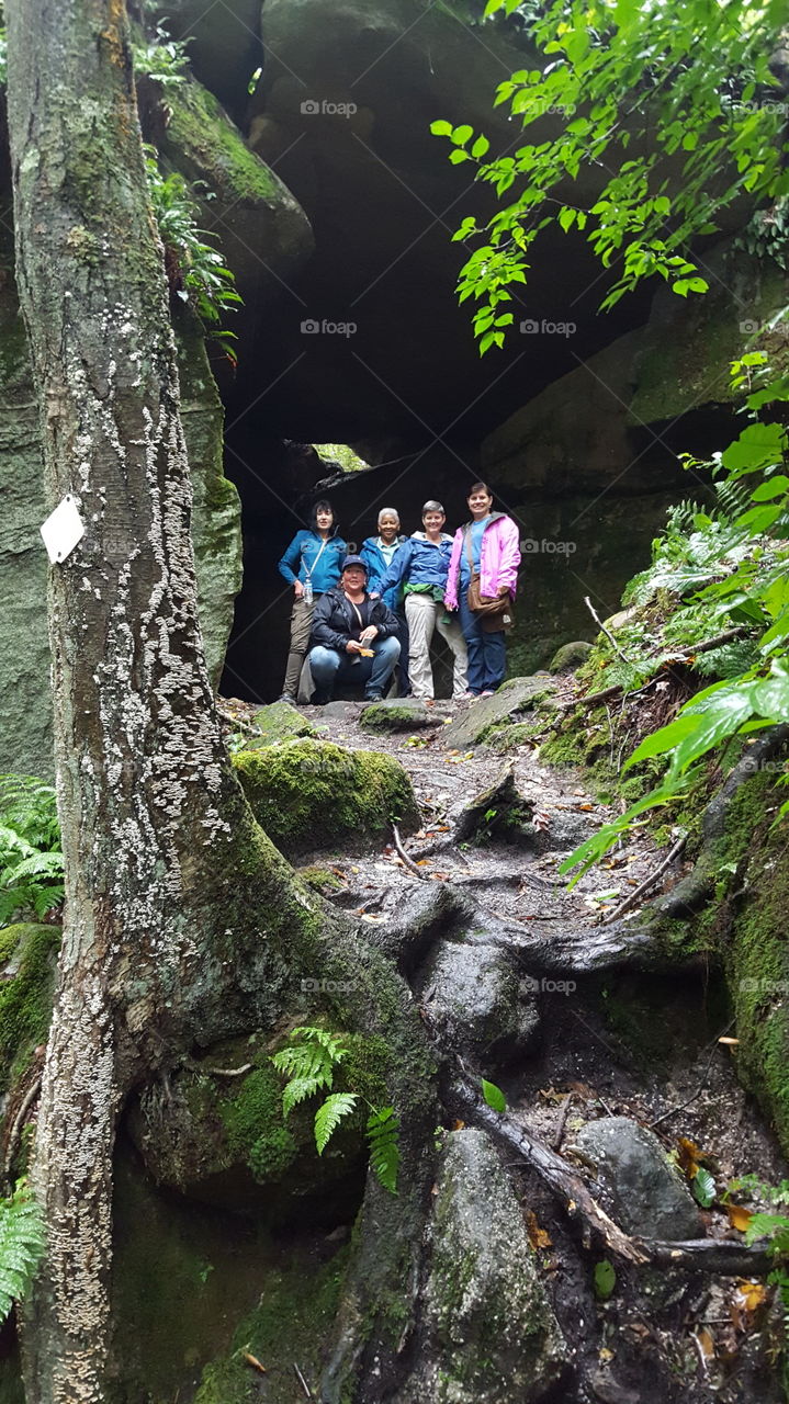 Women climbing rock formations during a hike in the forest.