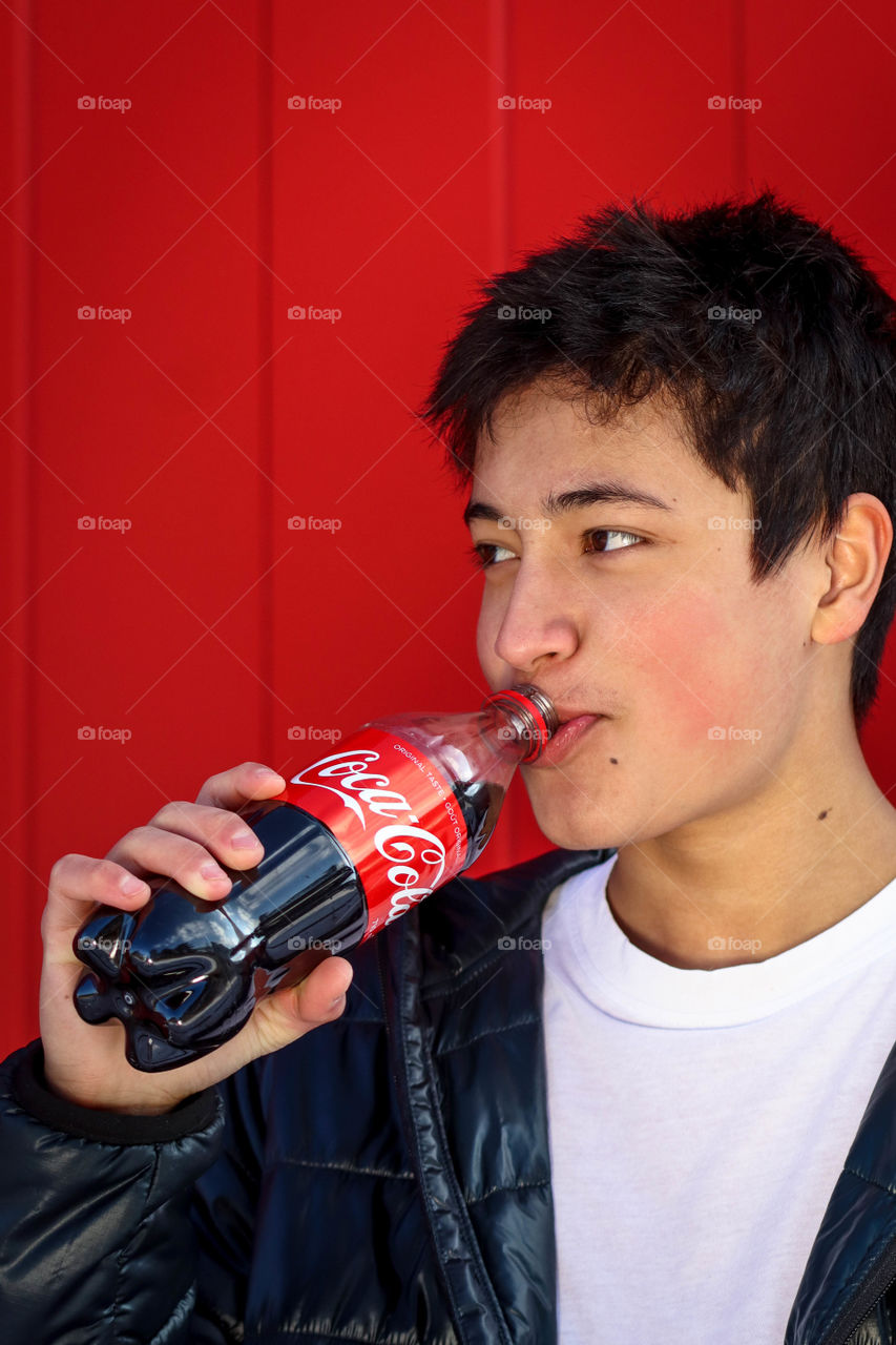 Young handsome man drinking Coca-Cola from a bottle