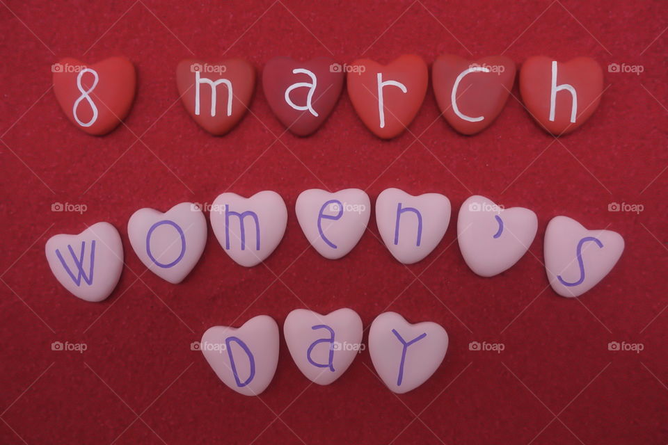 8 March, Women's Day with red and pink colored heart stones over red sand