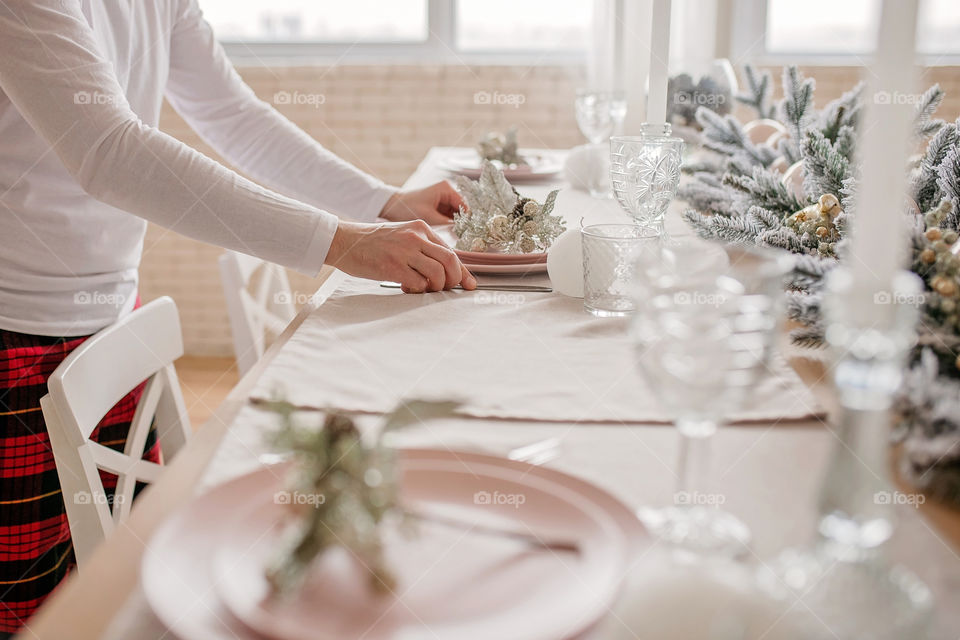 man sets a beautiful decorated winter table for a festive dinner.  Merry Christmas and Happy New Year.