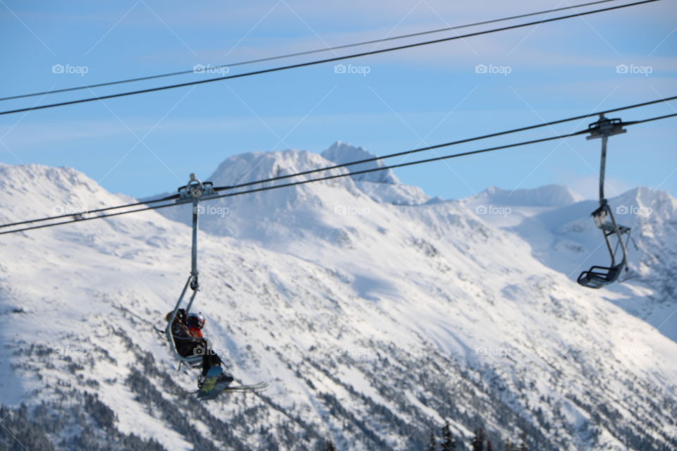 Winter 2019, mountains with snow and vivid skiers on a chairlift 