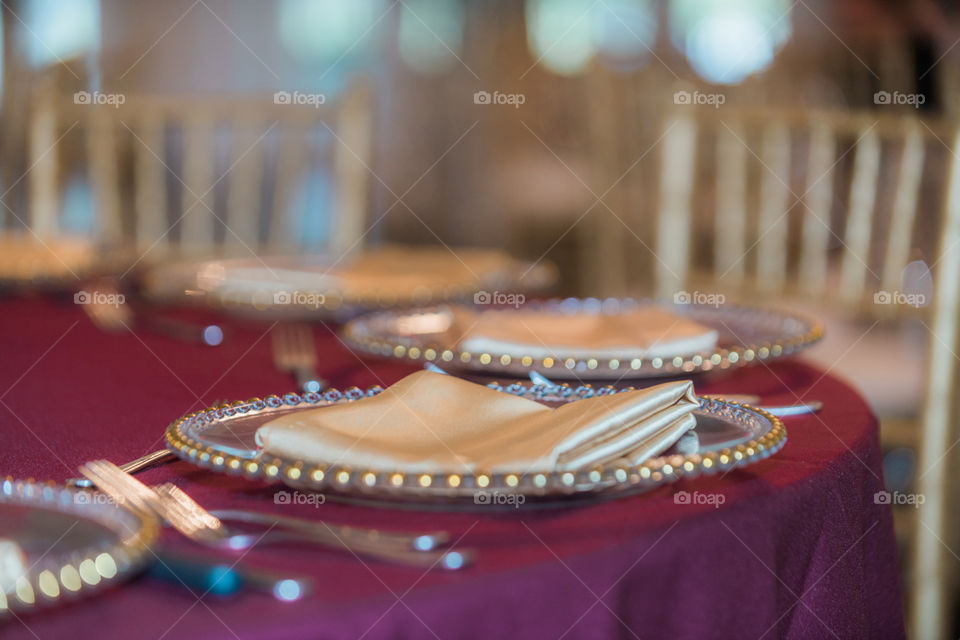 Gold plates and napkins on red linens tablecloth wedding reception table setting