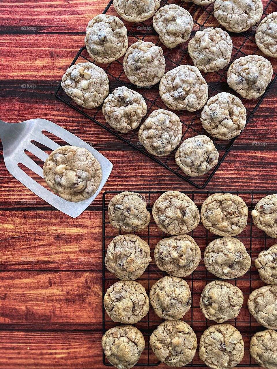 Freshly baked cookies on cooling racks, eating homemade cookies, freshly baked cookie on spatula with other cookies 