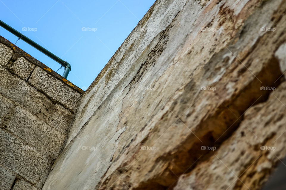 Stone wall from underneath against blue sky 