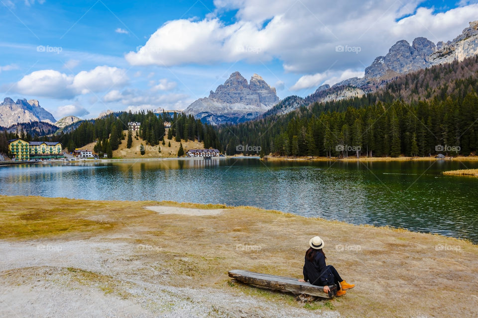 Rear view of a woman sitting on wooden log at lake side