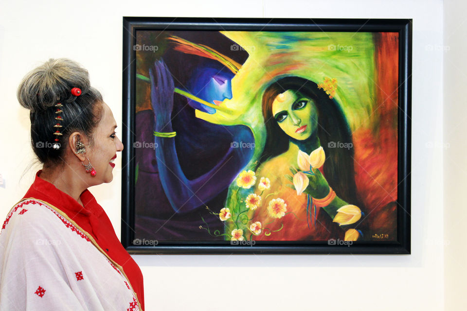 an admirer of art..woman admiring an oil painting of lord Krishna and Radha