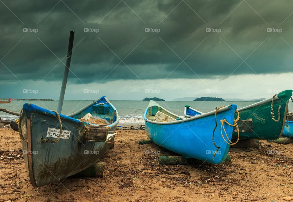 fishing boats parked at the beach with dark monsoon clouds hovering over the sky