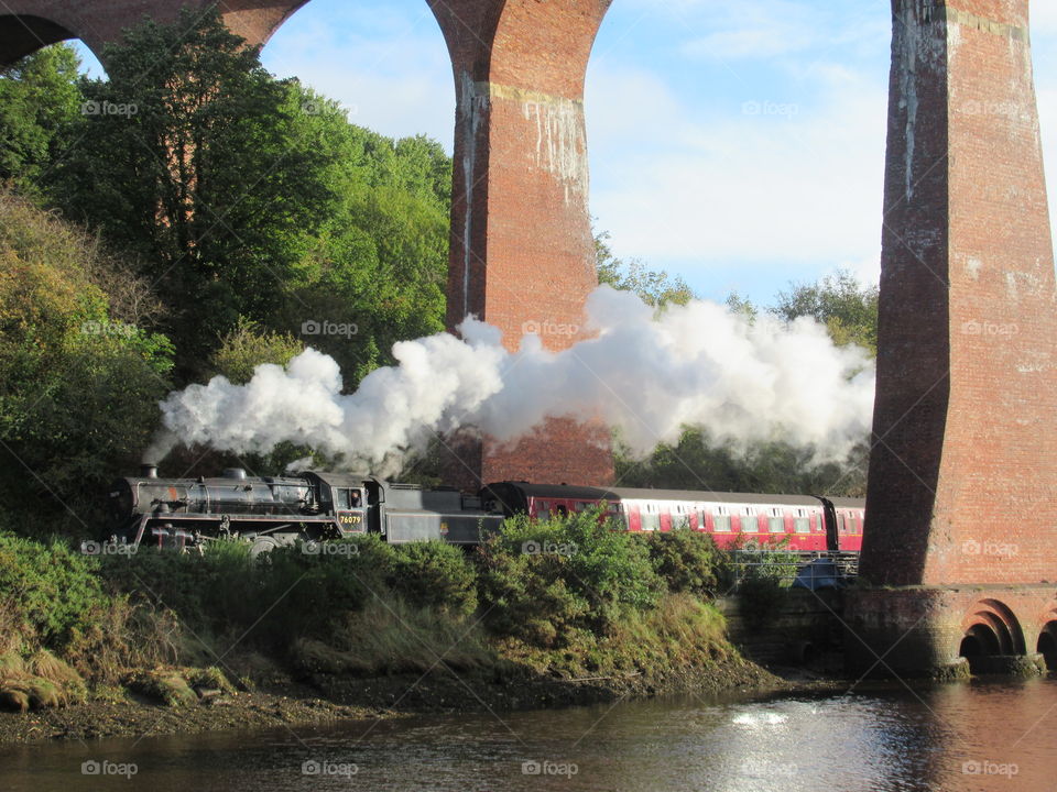 Steam train going through whitby viaduct, railway line next to river Esk