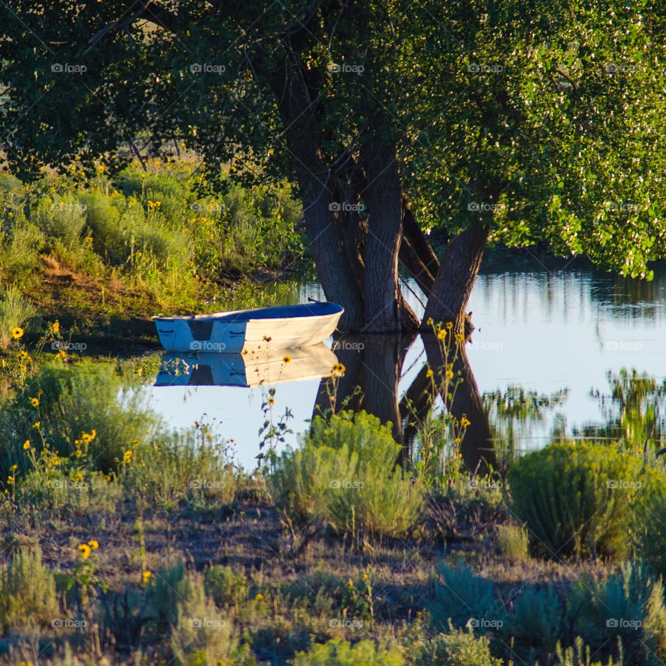 rowboat reflecting on a small run off catchment pond near Tierra Amarilla New Mexico at sunset