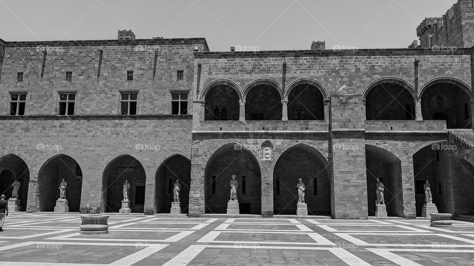 Beautiful view of the ancient historical castle of the twelve masters with arches, square windows, a large square and statues on the island of Rhodes in Greece, close-up side view. The concept of architecture and design of ancient castles.