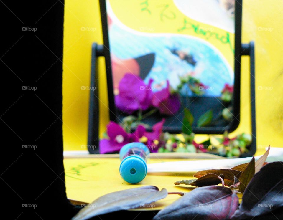 Work display and photo box with flowers and preparation for photo session with marker and flowers and leaves with small mirror with reflection of a photo printed paper.