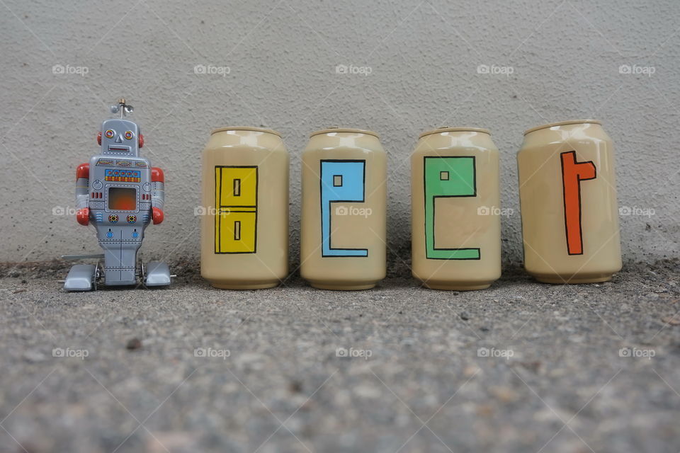 Beer text painted over beer cans with a tin toy robot