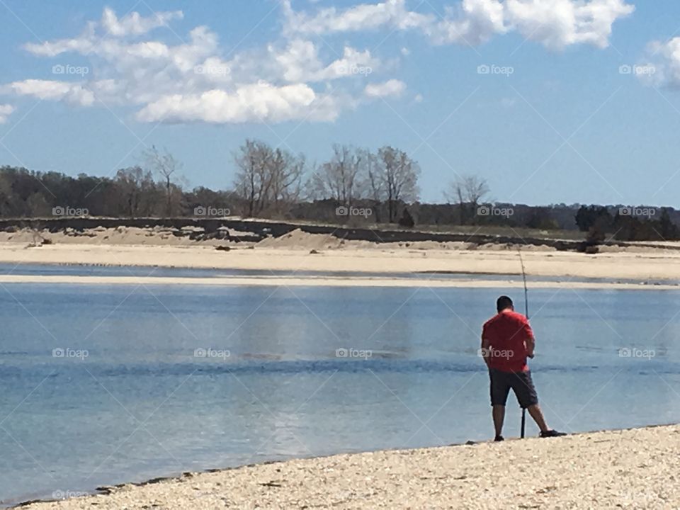 A man fishing on the beach. 